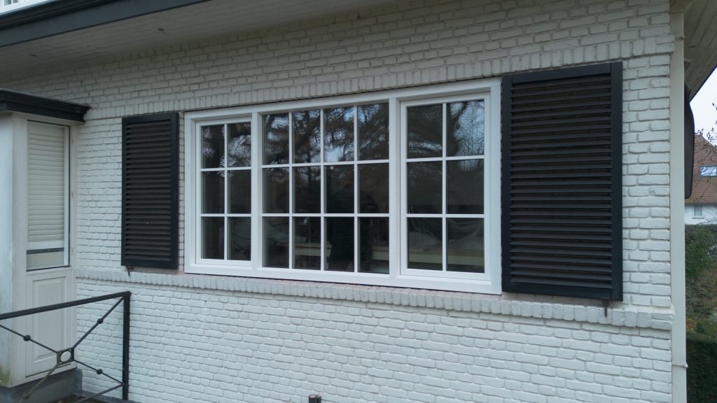 Nieuwe witte kozijnen met luiken in een lichte gevel