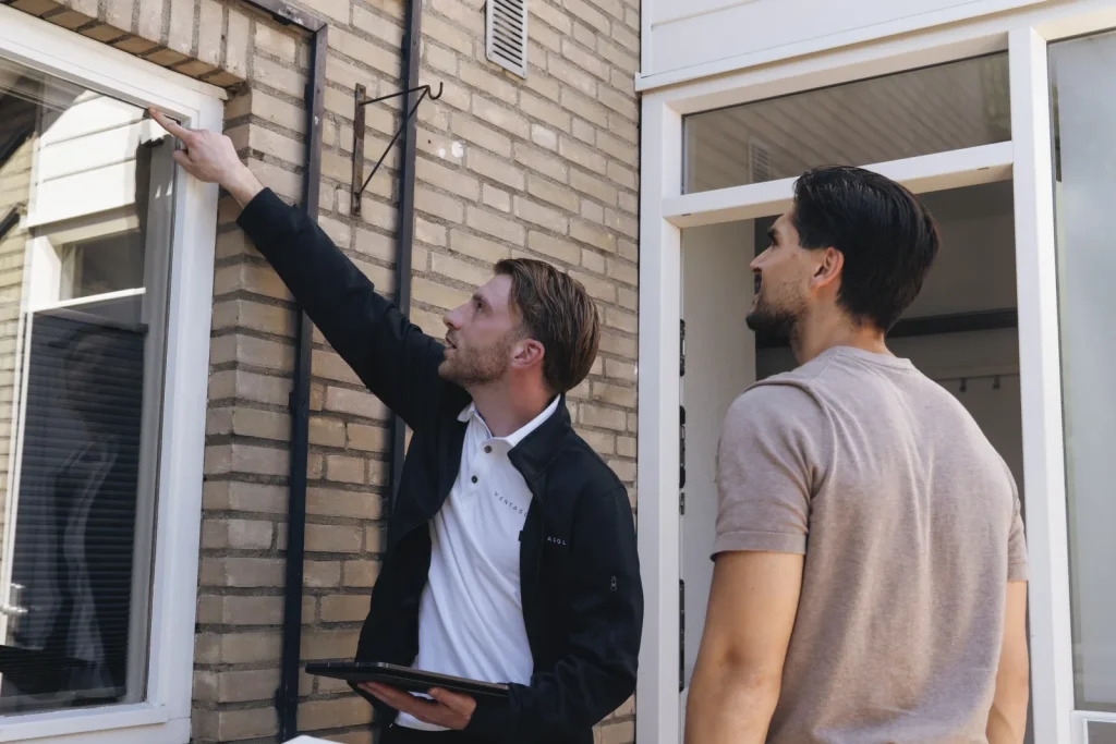 Adviseur wijst een raam aan bij de woning