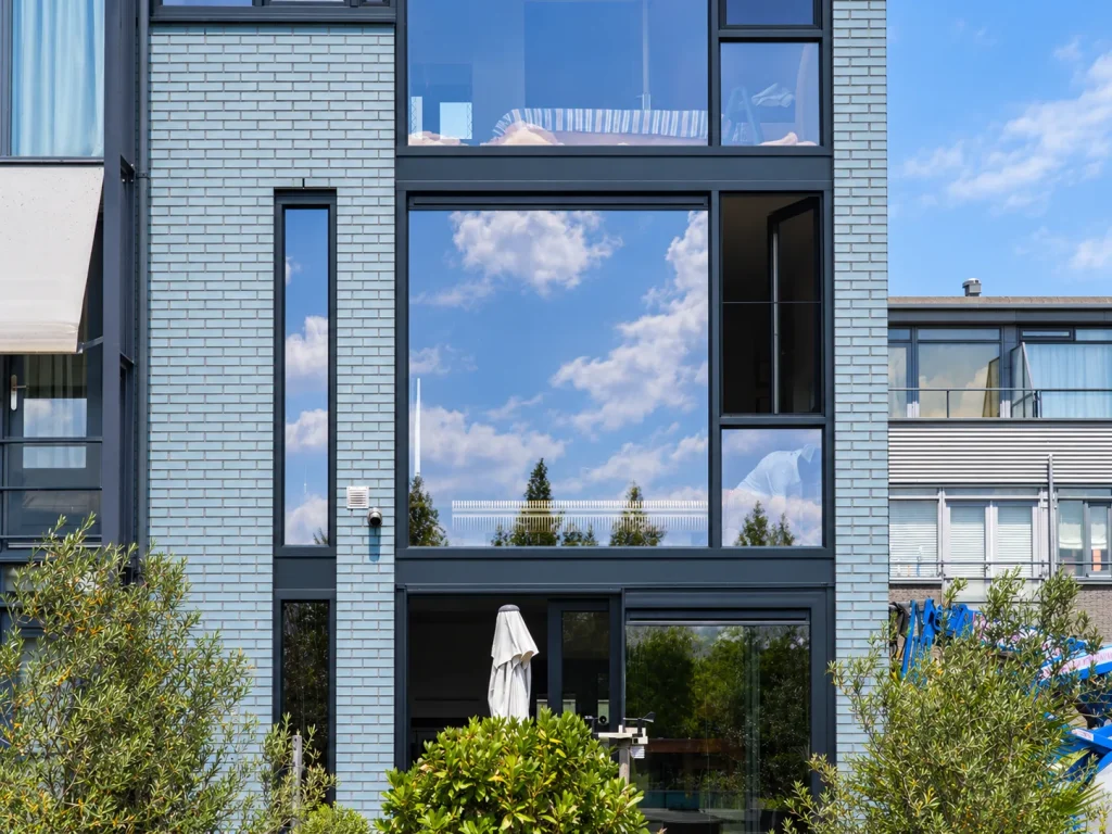 Moderne gevel met hoge antraciet kozijnen en glazen puien in Den Haag