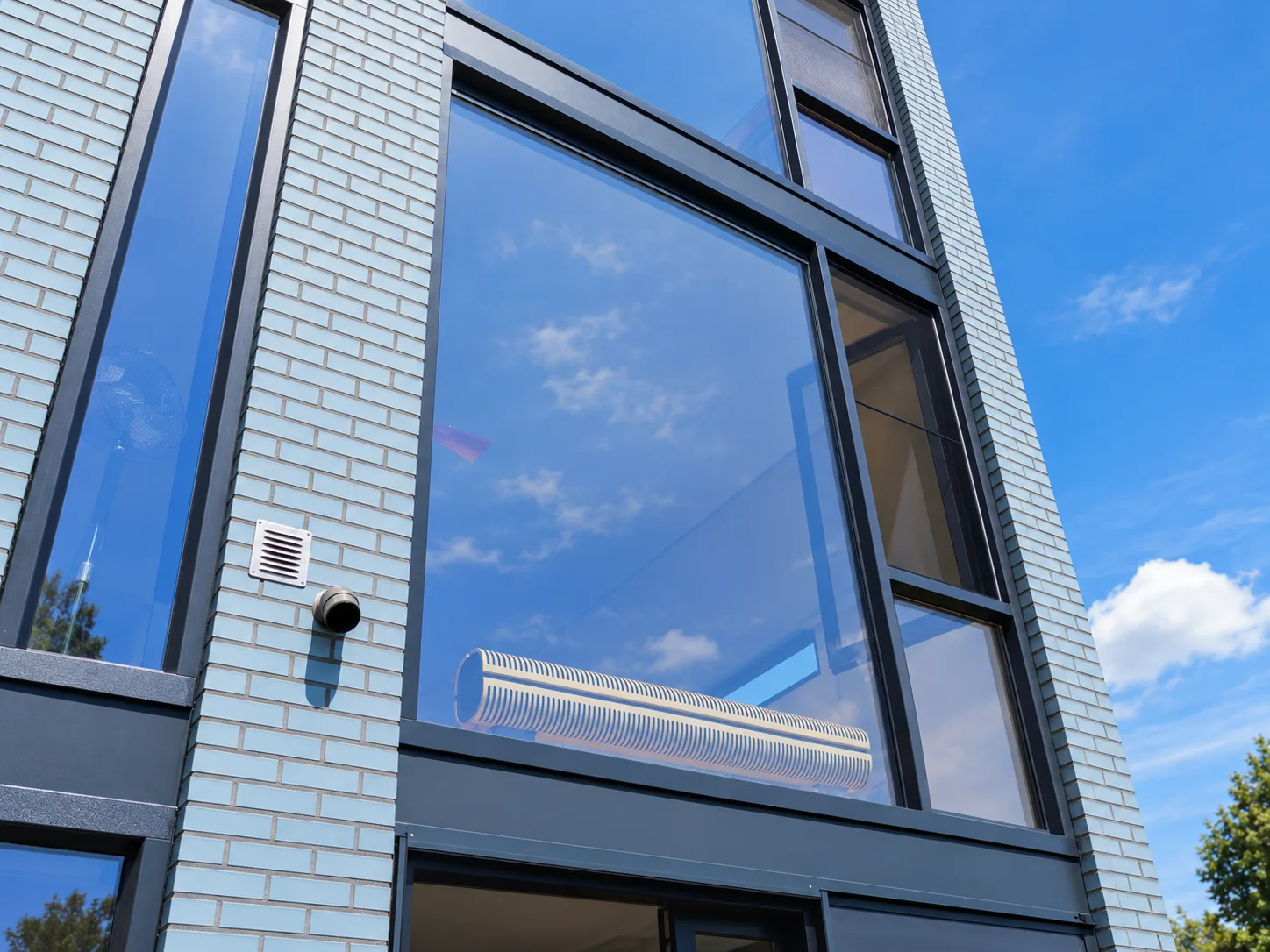Grote antraciet kozijnen met veel glas in een lichtblauwe gevel in Den Haag