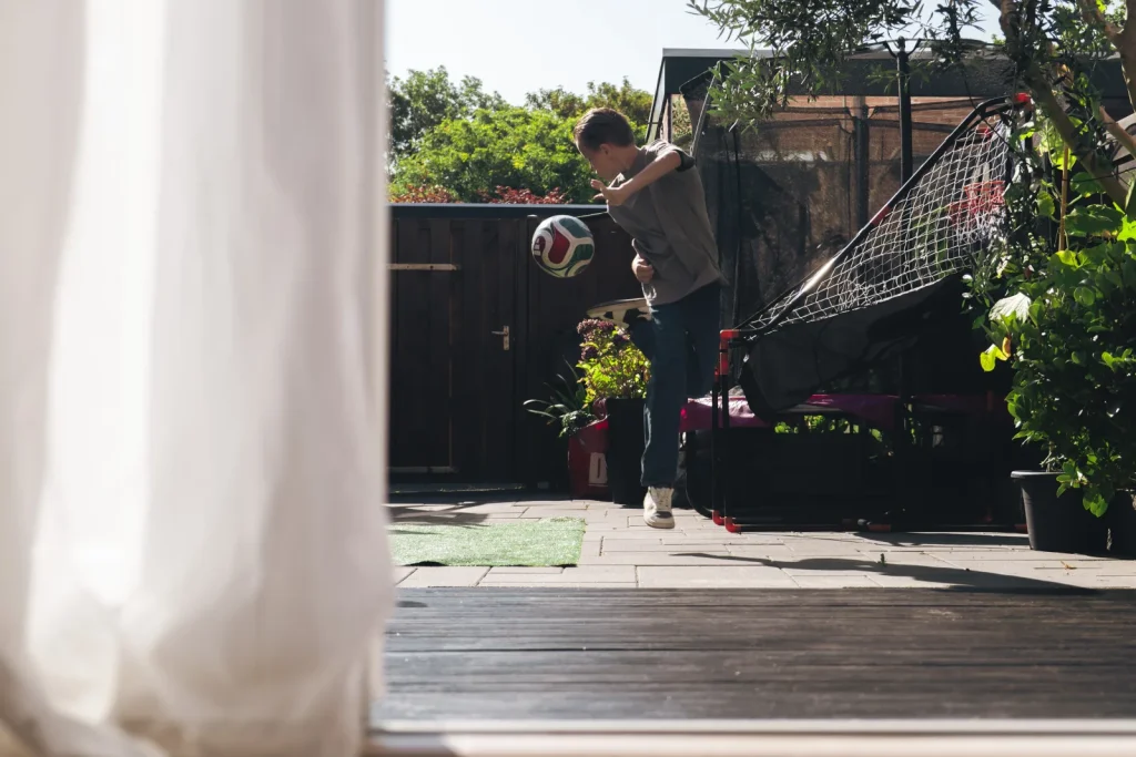 Kind speelt in de tuin, gezien vanuit de woonkamer