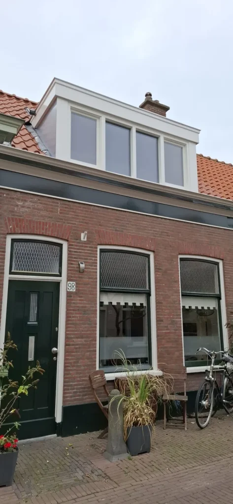 Klassieke witte houten dakkapel op een oude bakstenen woning