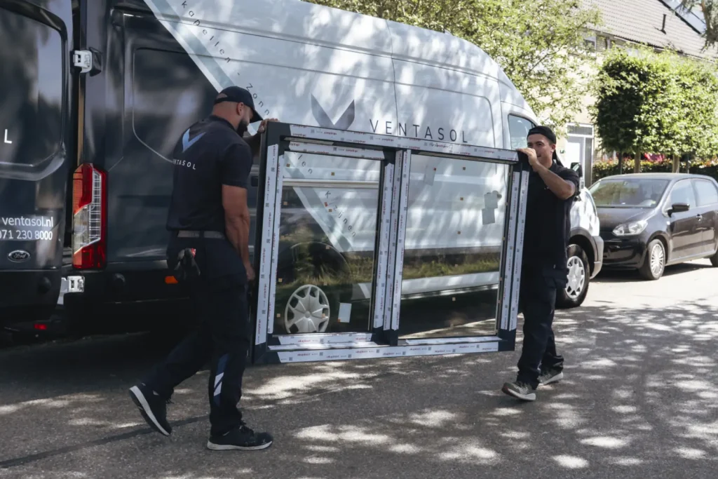 Monteurs dragen een kozijn uit de bedrijfsbus