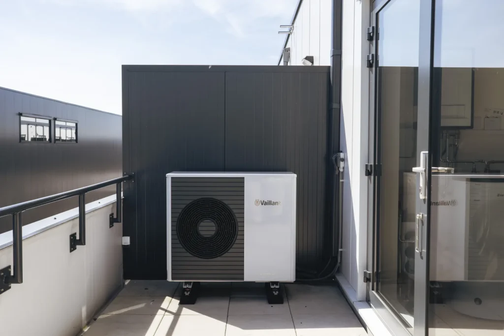 Buitenunit van een warmtepomp naast de gevel