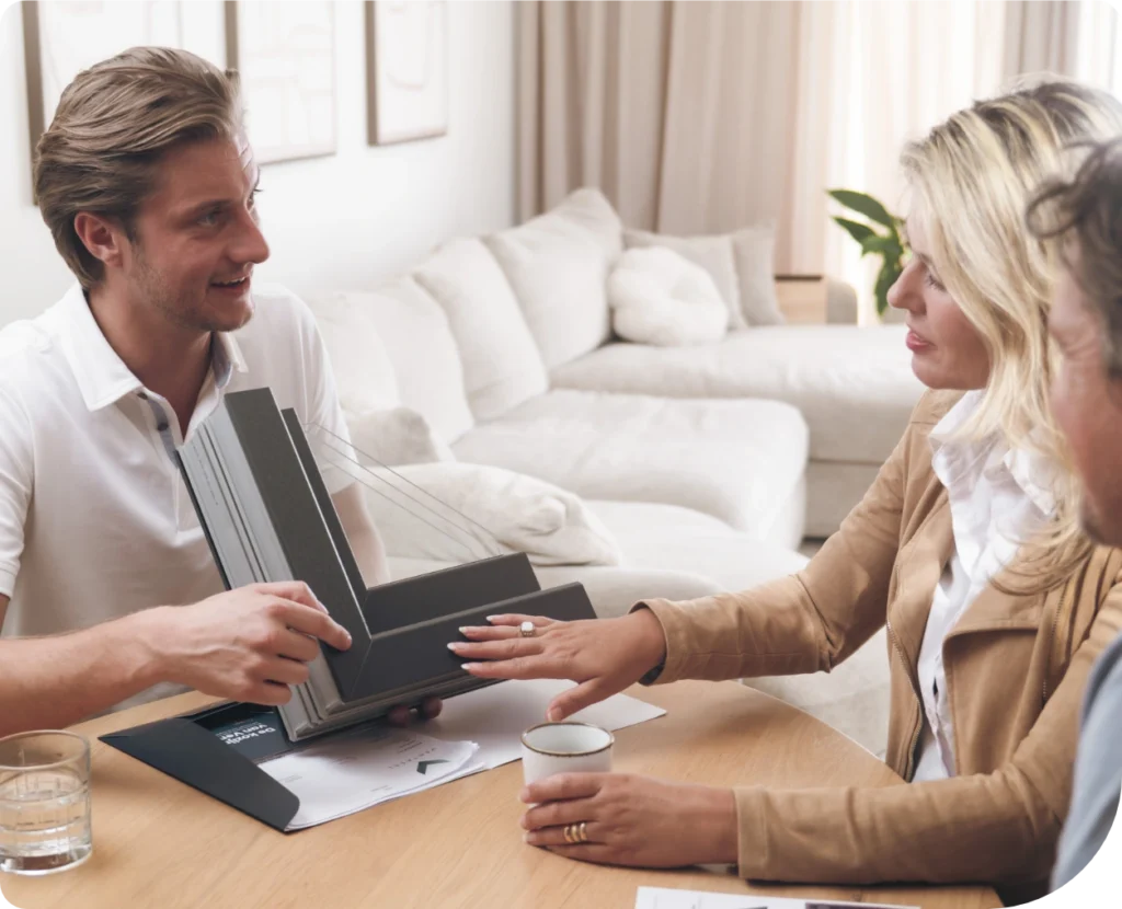 Adviseur van Ventasol toont kozijnprofielen aan een klant aan tafel